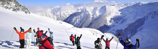 Group of skiers celebrating on snowy mountaintop.